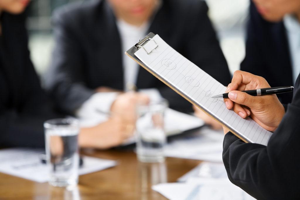 businesswoman's hand writing with other business people in background