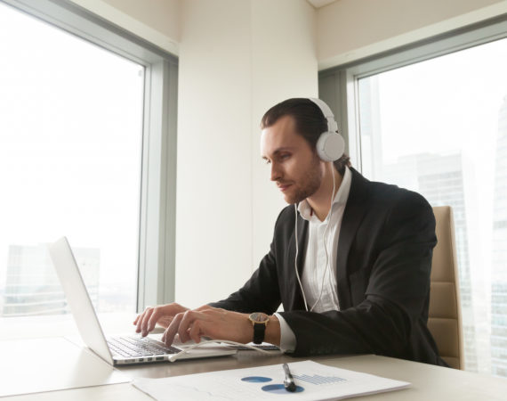 Businessman takes part in online meeting, conference, live stream, communicates with colleagues or partners via internet telephony. Guy listening music while working on laptop in office. Online study